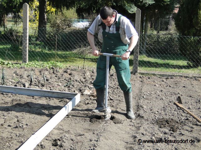 Aufbau Gewächshäuser, hier Löcher mit Erdbohrer für Punktfundament machen