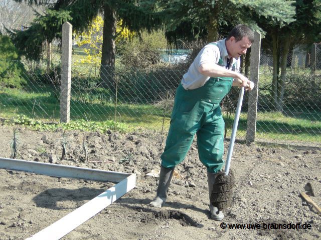 Aufbau Gewächshäuser, hier Löcher mit Erdbohrer für Punktfundament machen